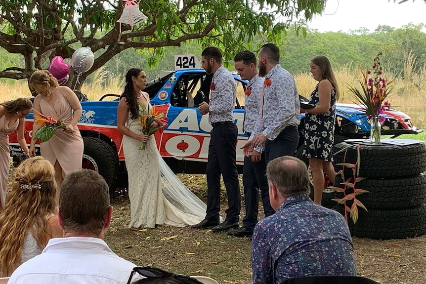 Bridal party stand in front of trophy truck