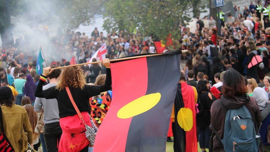 A woman holds the Aboriginal flag during an Invasion Day rally in Melbourne on Australia Day, January 26, 2015.
