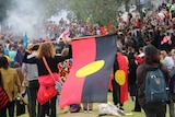 A woman holds the Aboriginal flag during an Invasion Day rally in Melbourne on Australia Day, January 26, 2015.