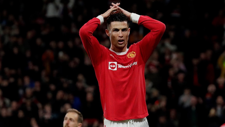 A soccer player wearing a red jersey puts his hands on his head during a game