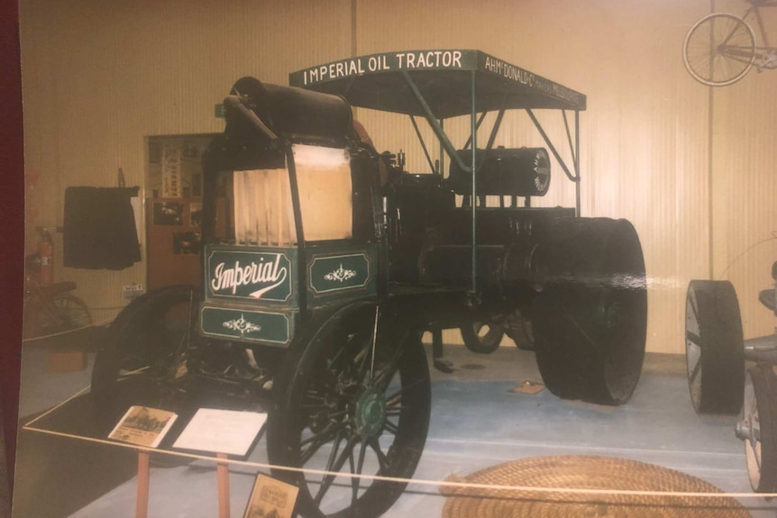 A green, steam engine lookalike, combustion tractor built in 1912 sits in a museum.