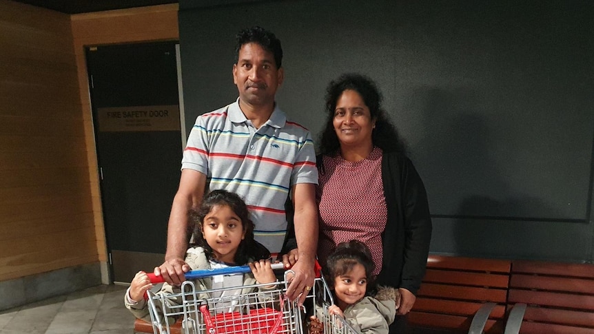 The Murugappan family stands outside a supermarket with a trolley