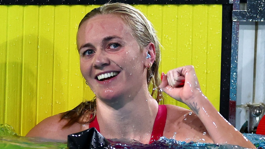 Swimmer Ariarne Titmus smiles and punches her first in the pool after winning a final