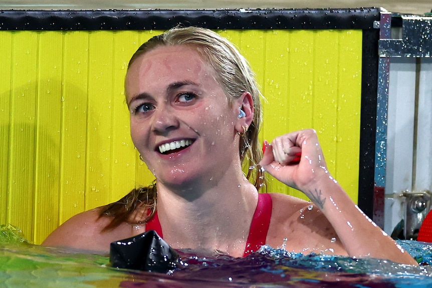 Swimmer Ariarne Titmus smiles and punches her first in the pool after winning a final