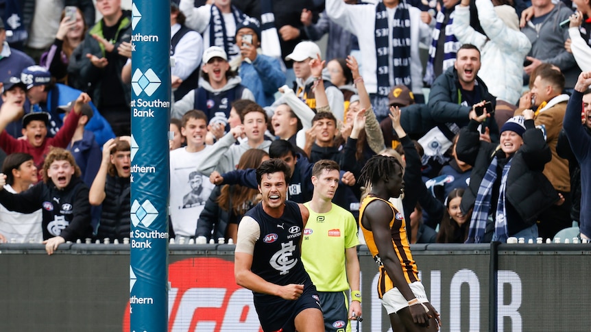 Jack Silvagni runs off smiling while Carlton fans behind him go nuts