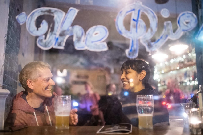 view from outside a restaurant of a man and woman enjoying a drink