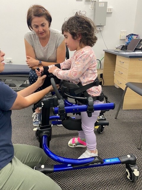 Chloe using a walking aid at rehabilitation therapy.