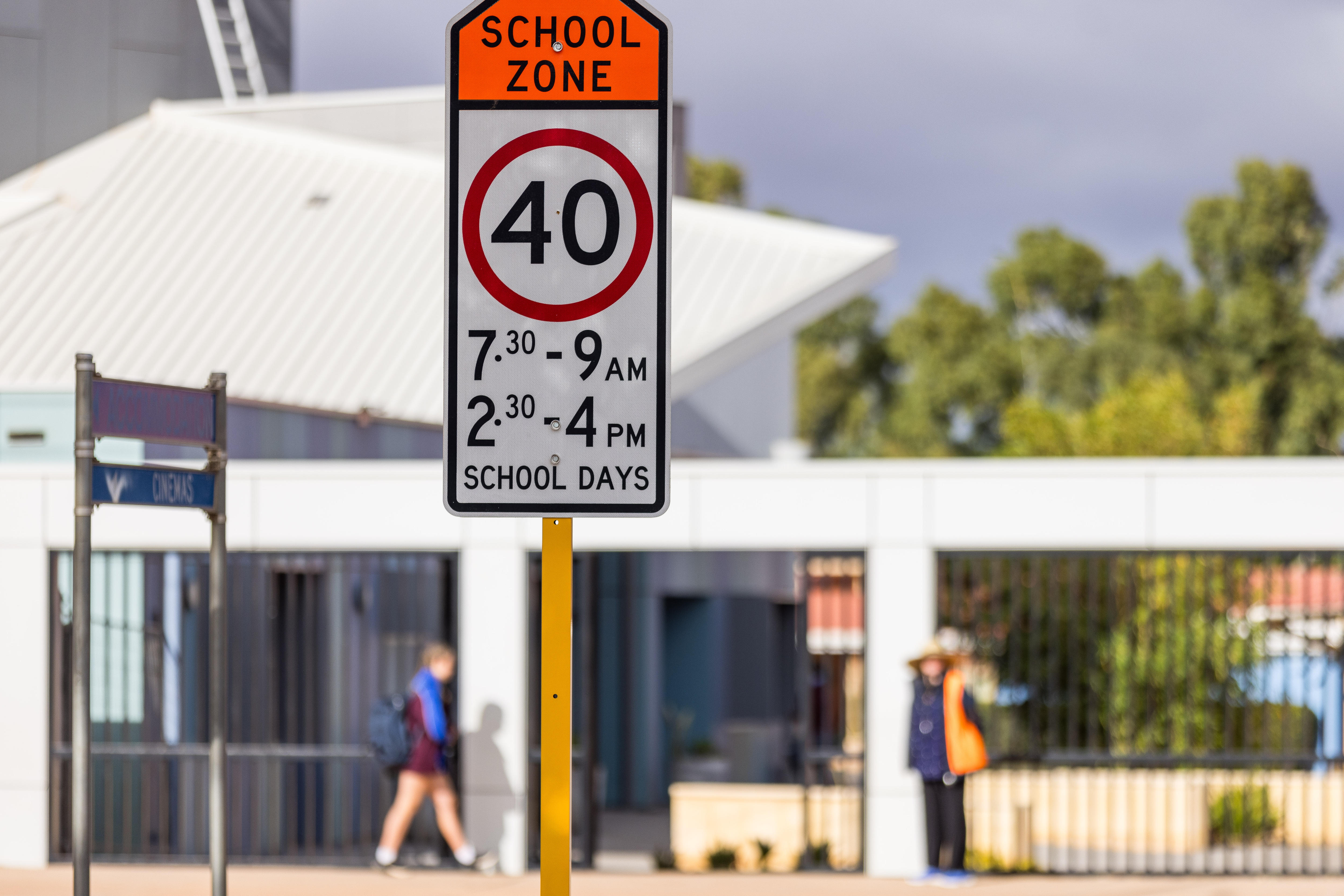 A 40km/hr school zone sign outside John Paul College in Kalgoorlie as a student walks through the entrance. 