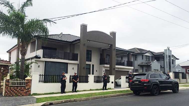Five policemen can be seen outside a two storey suburban property.
