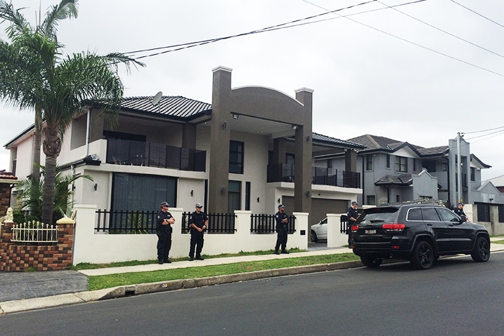 Five policemen can be seen outside a two storey suburban property.