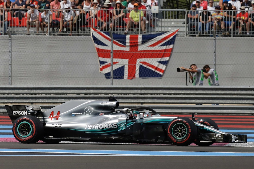 Lewis Hamilton drives past the English flag