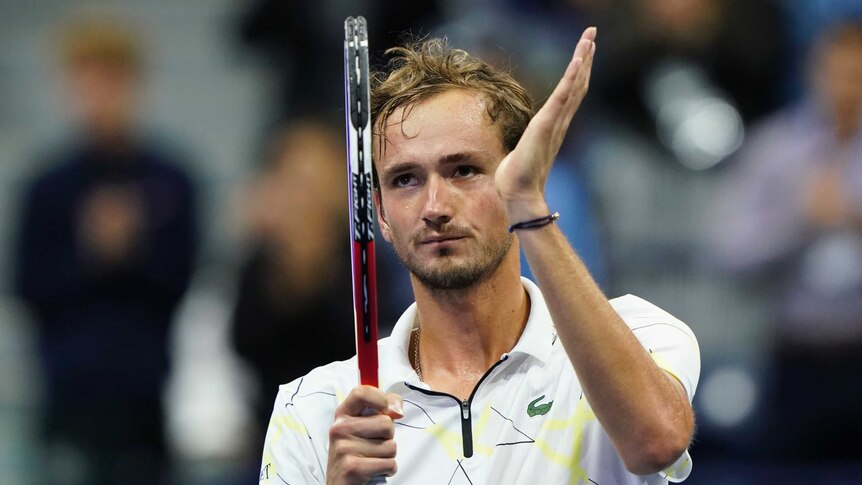 Daniil Medvedev claps his hand to his racquet and looks up at the crowd