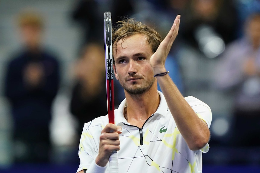 Daniil Medvedev claps his hand to his racquet and looks up at the crowd