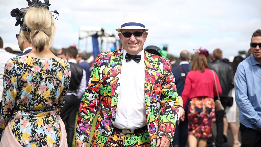 A man wearing a colourful patterned suit and a hat at the Melbourne Cup.
