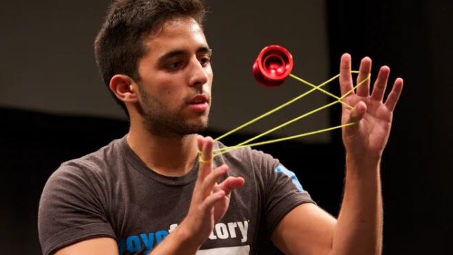 black man with red yoyo spinning in front of his face with a yellow string between his fingers