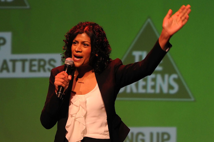 Greens leader Samantha Ratnam speaks into a microphone ata party event.