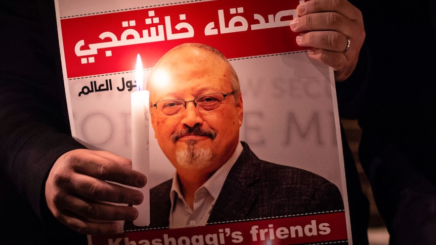 A photo of someone holding a picture of Jamal Khashoggi with a candle