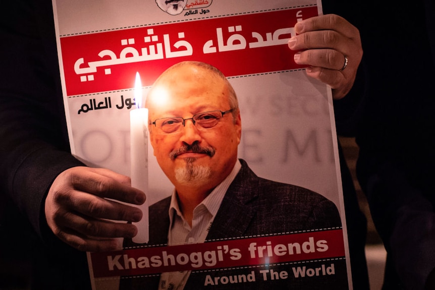 Een foto van iemand die een foto van Jamal Khashoggi vasthoudt met een kaars
