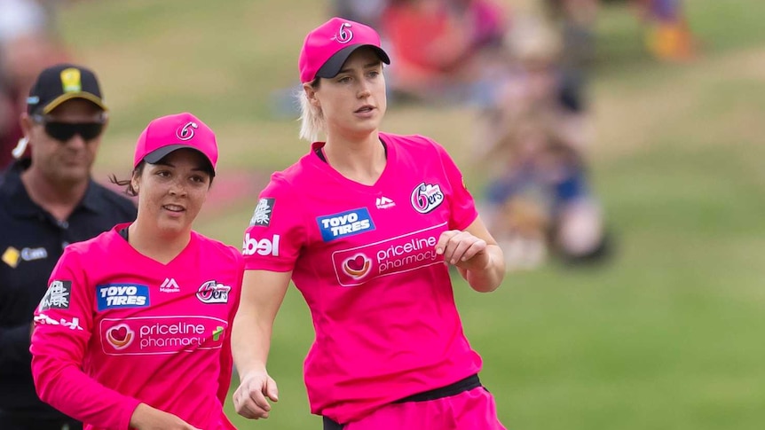 Ellyse Perry (centre) and Lauren Smith (left) of the Sydney Sixers celebrate a WBBL wicket with teammates.