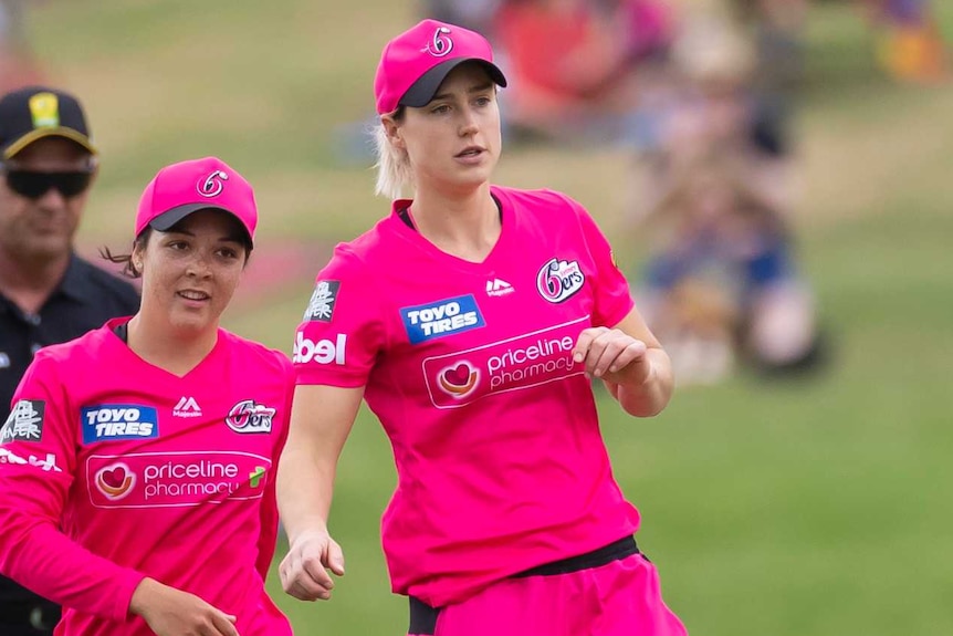 Ellyse Perry (centre) and Lauren Smith (left) of the Sydney Sixers celebrate a WBBL wicket with teammates.