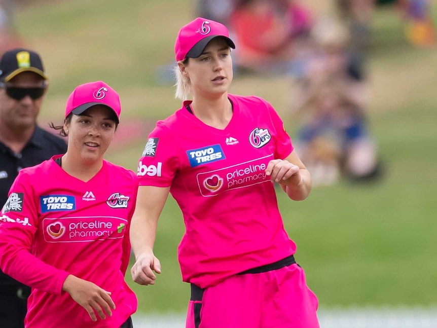 Ellyse Perry (centre) and Lauren Smith (left) of the Sydney Sixers celebrate a WBBL wicket with teammates.