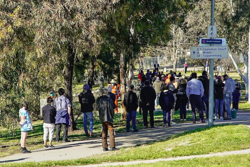 A long line of people stretches through a park at a Canberra testing clinic
