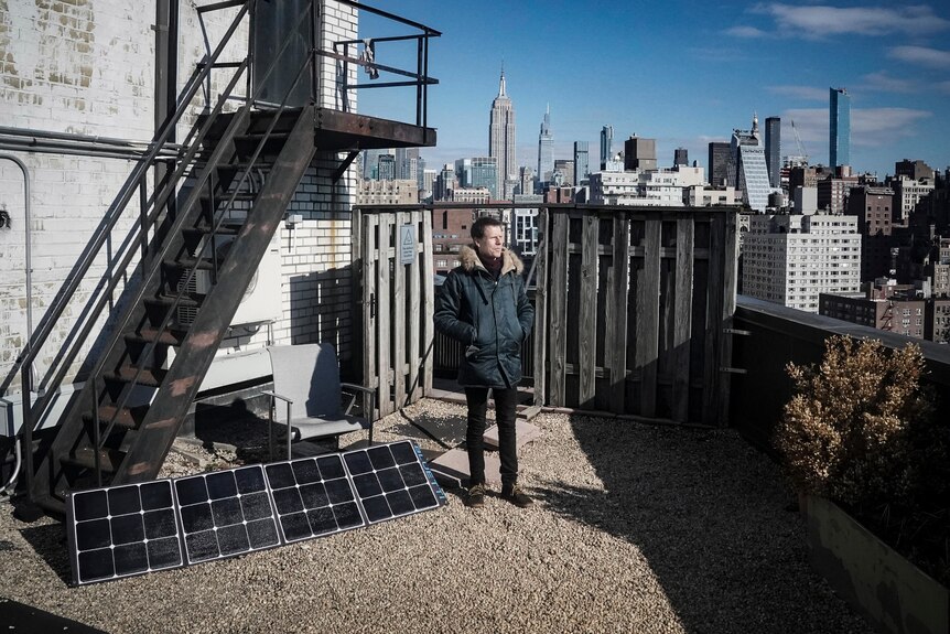 a man stands in the sun on the rooftop of his apartment in New York City