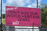 A large pink sign on top of a trailer which reads "Speak up, don't risk our world heritage jewel, vote no to a Daintree bridge"