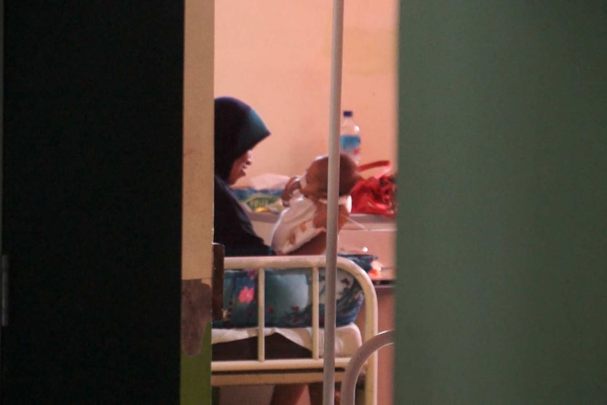 Mother sits in hospital and holds baby diagnosed with foetus in foetu condition.