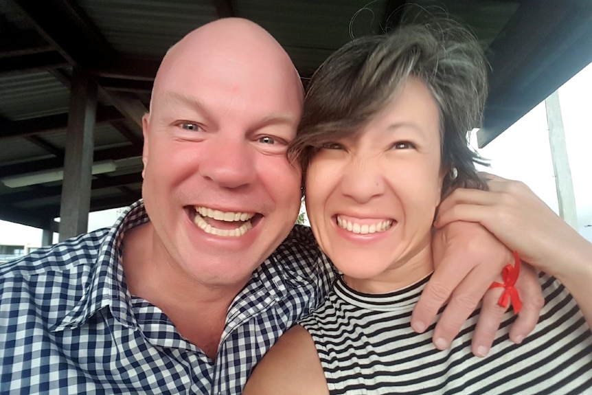 A man and woman hug tightly in a selfie photo, with his arm around her neck, close up to the camera both looking ecstatic