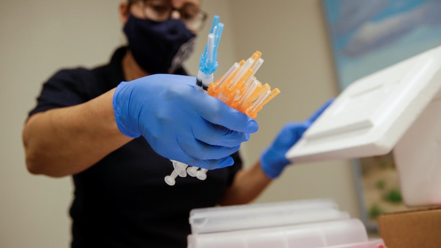 A healthcare worker holds a bunch of vaccine syringes.