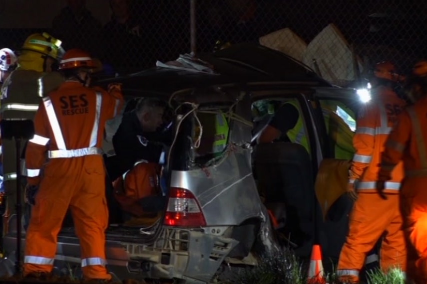 Emergency services examine the wreckage of a car.