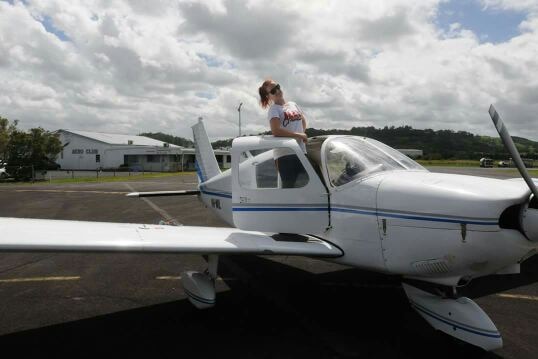 Suicide survivor Hayley Purdon standing outside of the door of a small aeroplane on a cloudy day.