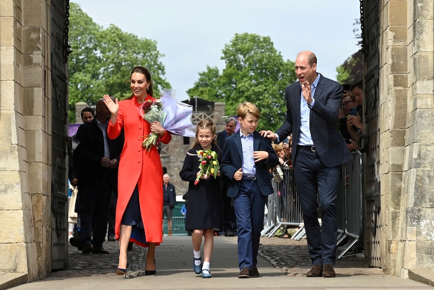 Kate, Charlotte, George and William smile and wave to crowds. Charlotte and George hold flowers and look nervous.