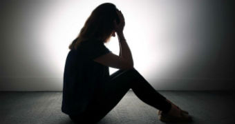 Stock image of a woman holding her head in her hands.