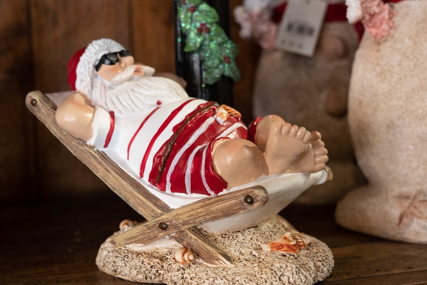 Summer Santa ornament leaning back on a deck chair.