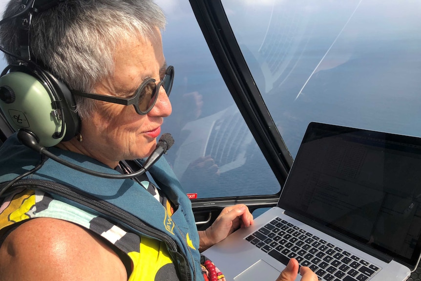 A middle-aged woman in the seat of a helicopter