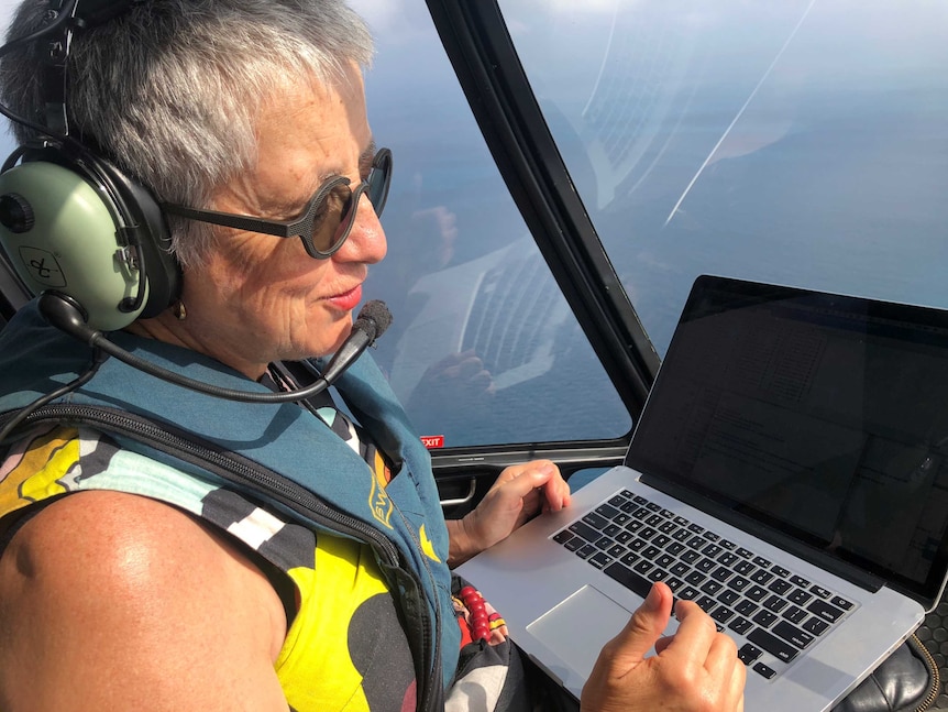 A middle-aged woman in the seat of a helicopter