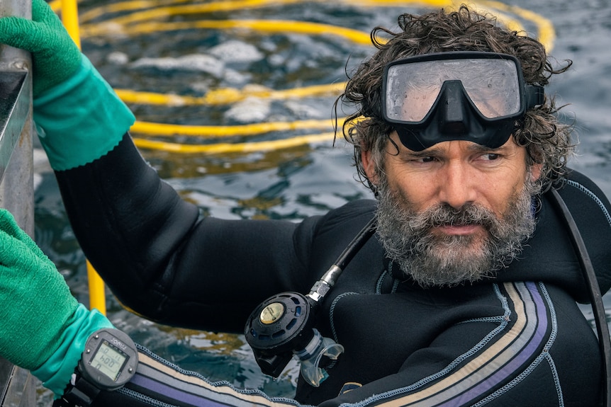 Actor Eric Bana wears diving gear and looks out over the water in a still taken from his new film, Blueback.