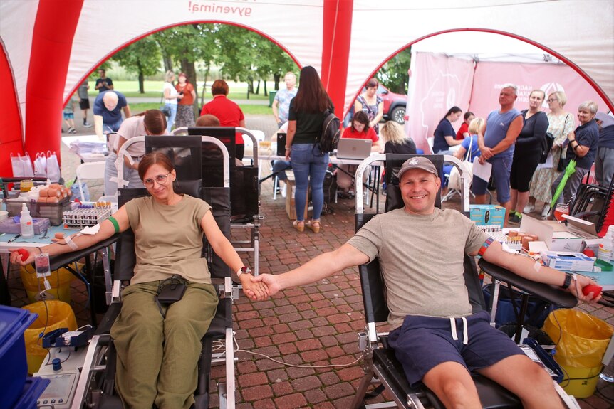 A couple holding hands at a blood donation drive