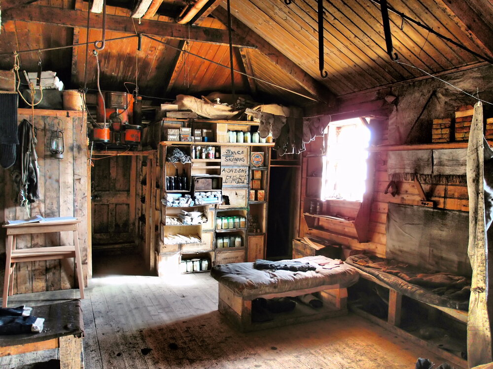 The wooden interior of Shackleton's hut, with shelves full of equipment and provisions.