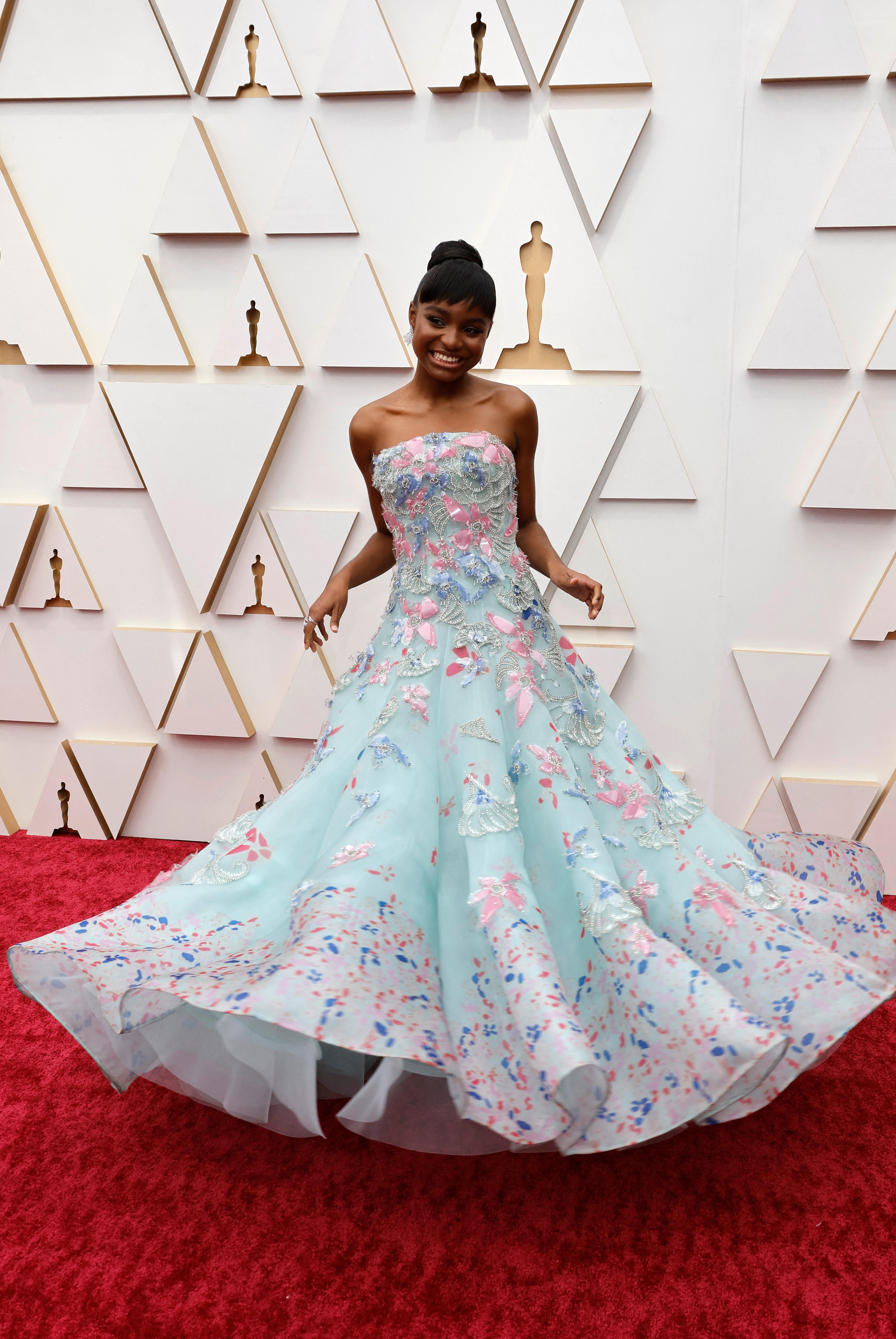 Saniyya Sidney swirls her blue ballgown with pink flowers on it on the red carpet at the oscars