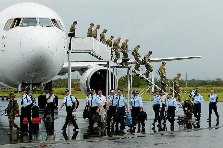 Soldiers and police officers disembark from a plane