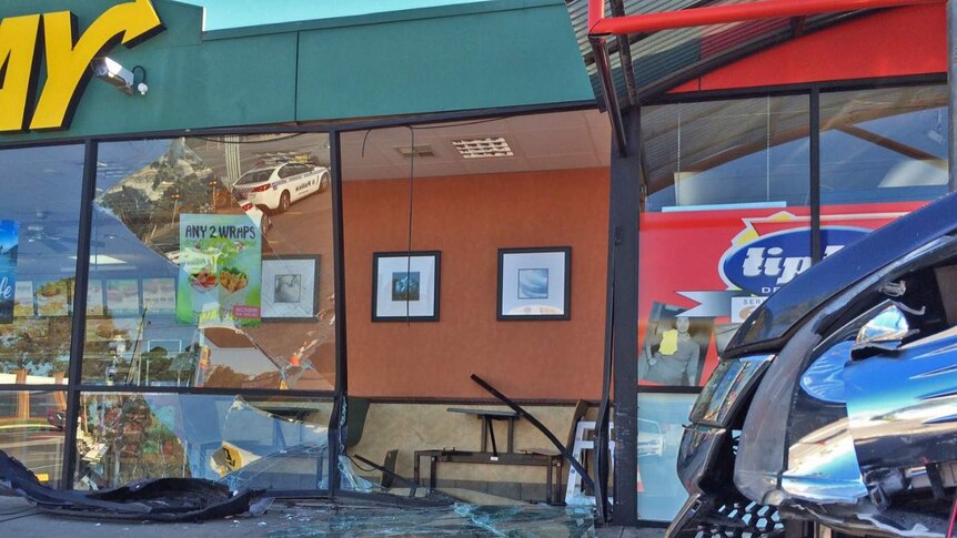 Broken front window of a Subway store after a car hit it