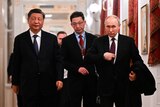 Xi Jinping and Vladimir Putin walk down a hallway in the Kremlin.