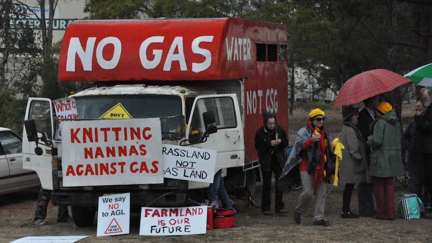 People protesting a coal seam gas project display signs with anti-CSG slogans.