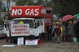 People protesting a coal seam gas project display signs with anti-CSG slogans.