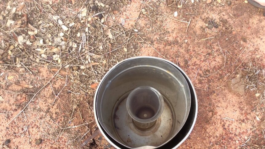 Bare earth with a full, ground rain gauge in the centre of the picture, taken at Anna Plains station south of Broome