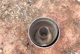 Bare earth with a full, ground rain gauge in the centre of the picture, taken at Anna Plains station south of Broome