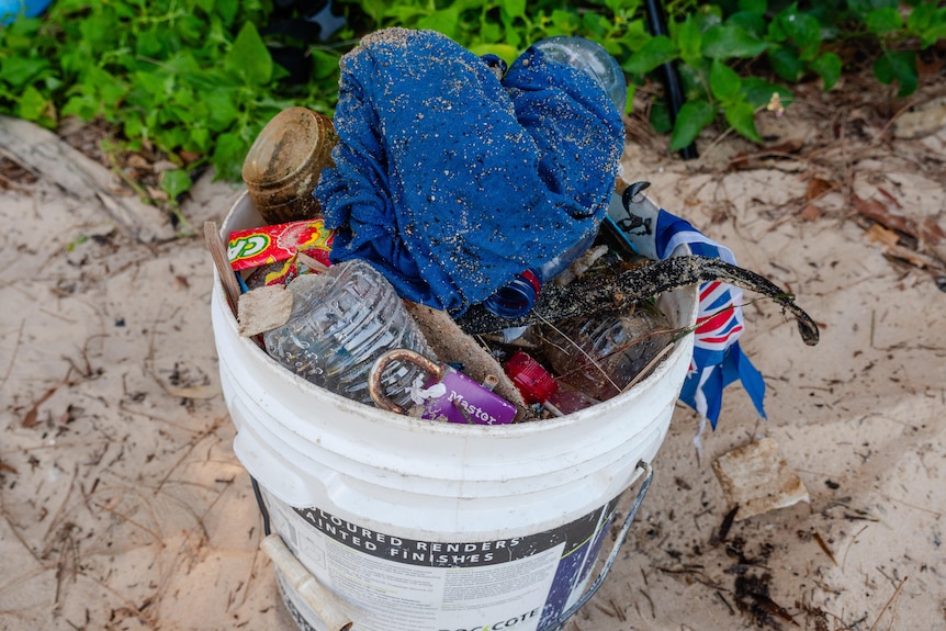 A bucket filled with plastic rubbish at a beach